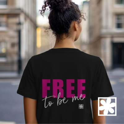 A woman standing facing away from the camera wearing a T-shirt with the phrase "free to be me" on the back.